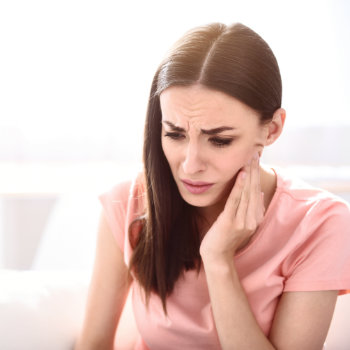 Brunette woman holding cheek tooth pain Emergency Dental CareDuluth